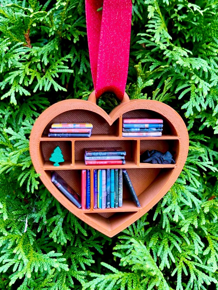 Heart-shaped ornament with books and a tree on a green leaf background
